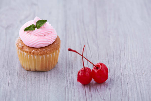 istock Delicious cupcake and cherries on wooden background 996165800