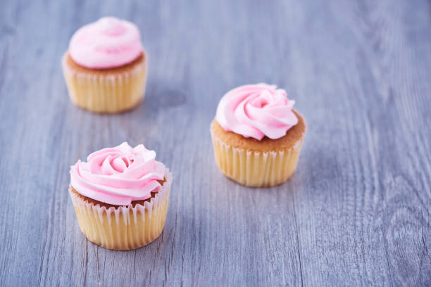 istock Three delicious cupcakes on wooden background 996165912