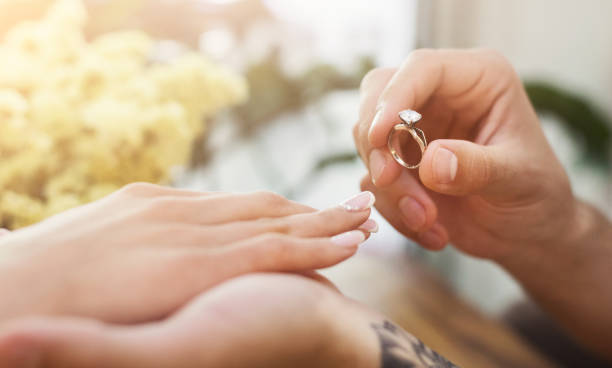 istock Man putting on girl finger engagement ring 996167162