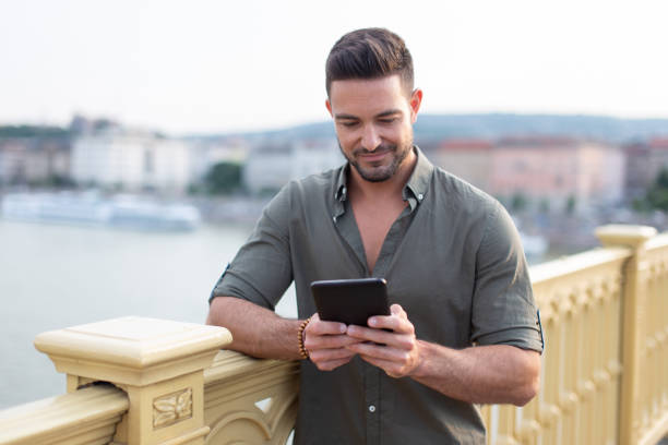 istock Young caucasian man using tablet outdoors in city 996172950