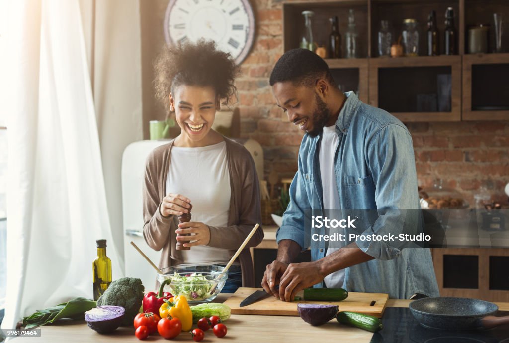 Casal negro salada na cozinha a preparar a rir - Foto de stock de Cozinhar royalty-free