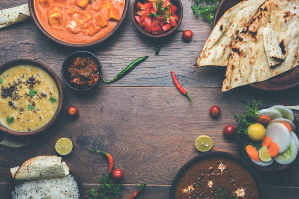 assorted indian food for lunch or dinner, rice, lentils, paneer, dal makhani, naan, chutney, spices over moody background. selective focus - main course imagens e fotografias de stock