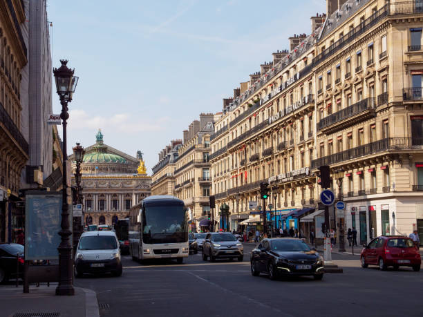 Avenue de l'Opera during rush hour, Paris, France PARIS, FRANCE - May 9, 2018: Wide angle view down the Avenue de l'Opera, with Palais Garnier at the end of the street during rush hour. Travel and urban landmarks editorial. place de lopera stock pictures, royalty-free photos & images