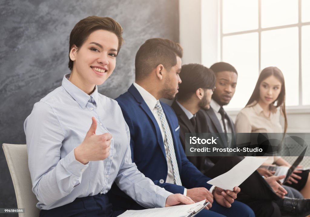 Multiracial people waiting in queue preparing for job interview Cheerful woman showing thumb up, multiethnic people waiting in queue. preparing for job interview and reading cv, copy space Job Search Stock Photo