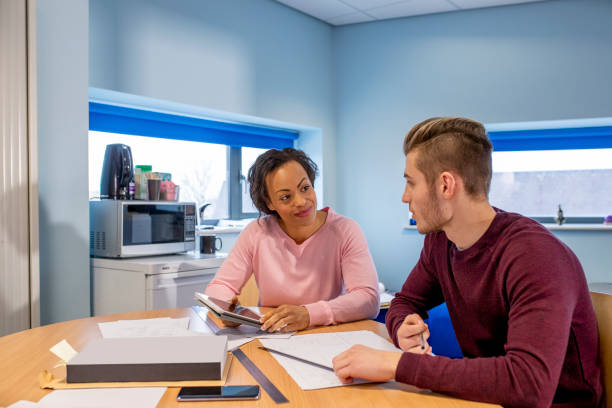 Progress Review Meeting with his Tutor A teenage boy sits down for a progress meeting and discussion with his engineering tutor. progress report stock pictures, royalty-free photos & images