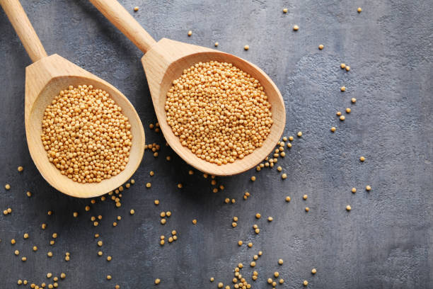 istock Mustard seeds in wooden spoon on grey table 996194618