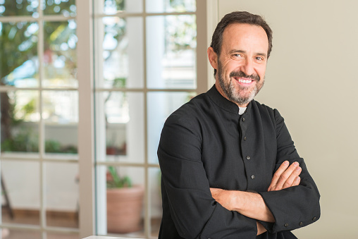 Christian priest man with a happy face standing and smiling with a confident smile showing teeth