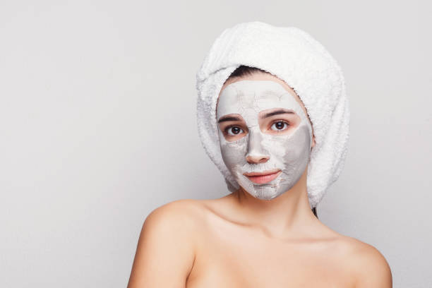 istock Beautiful girl with applied clay mask at grey background 996196150