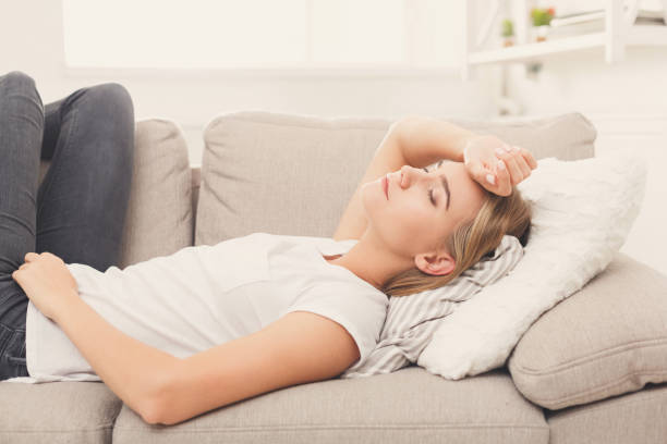 istock Sad blonde girl feeling pain lying on sofa 996201096