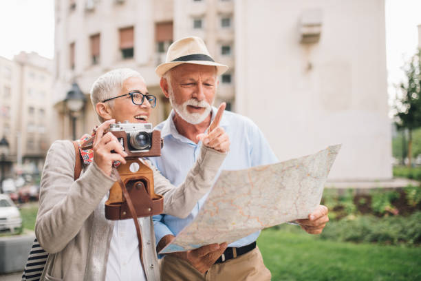 istock Happy mature woman holding camera and talking to the man with a map 996238708