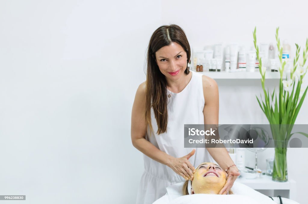 face scrub treatment Beautiful woman having a facial cosmetic scrub treatment from professional dermatologist at wellness spa Beautician Stock Photo