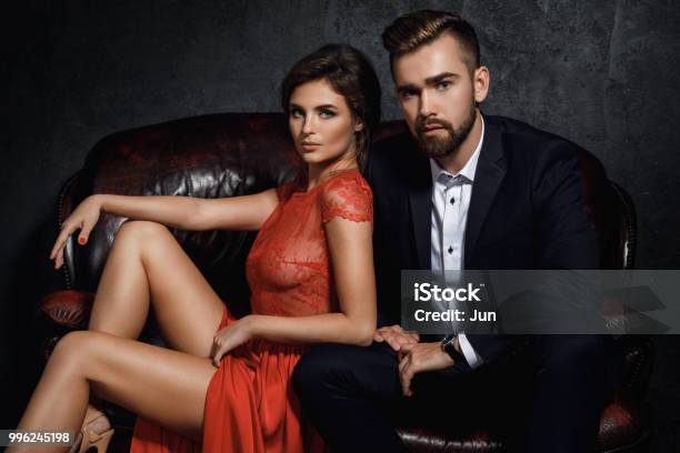 Attractive Young Couple Is Sitting On The Leather Sofa Stock Photo - Download Image Now