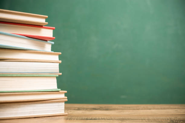 istock Textbooks on wooden school desk with chalkboard. 996251056