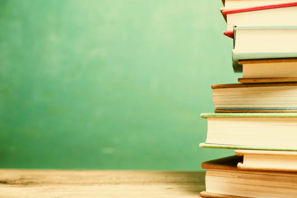 istock Textbooks on wooden school desk with chalkboard. 996251506