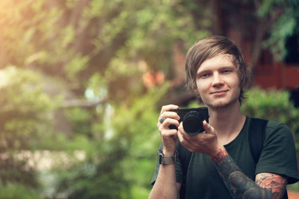 istock Handsome young man holding digital camera and smiling 996261390
