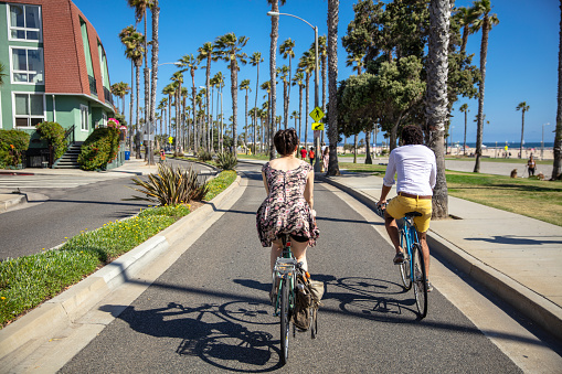 Rear view of a man and woman riding bicycles in Santa Monica, California.