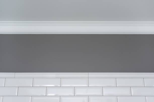 istock Gray painted wall, white ceiling molding and ceramic decorative tiles small white glossy brick. Fragment of the walls of the bathroom, toilet, kitchen. 996279398