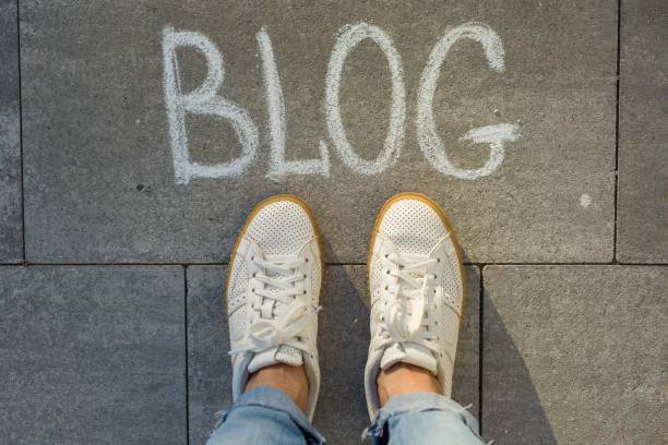 istock View from above, female feet with text blog written on grey sidewalk 996282790