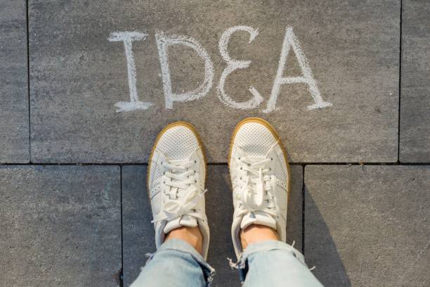 istock View from above, female feet with text idea written on grey sidewalk 996284576