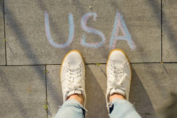 istock View from above, female feet with text USA written on grey sidewalk 996284722