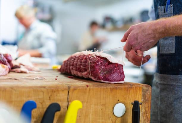 Food preparation in traditional UK Butchers shop. stock photo