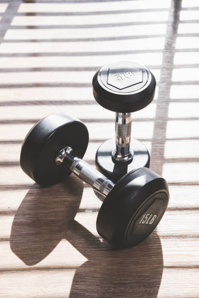 istock Dumbbell set indoor on brown wood floor with hard shadow from large window 996302330
