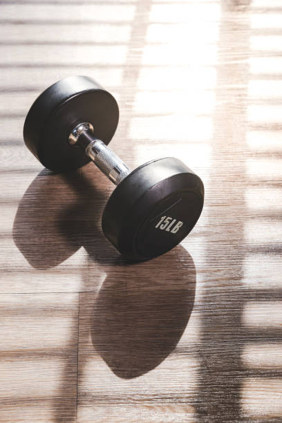 istock Dumbbell set indoor on brown wood floor with hard shadow from large window 996302344