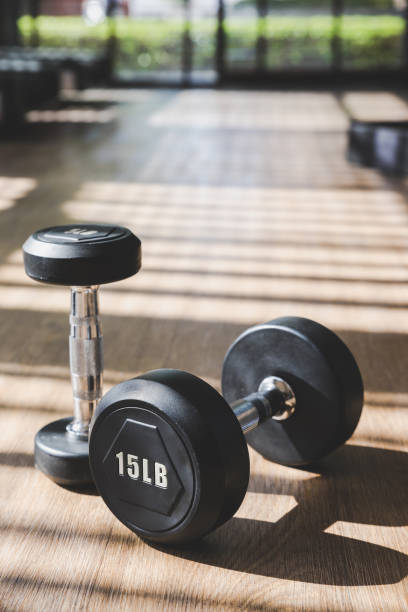 istock Dumbbell set indoor on brown wood floor with hard shadow from large window 996302346