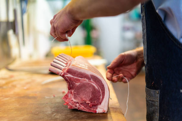 Food preparation in traditional UK Butchers shop. stock photo