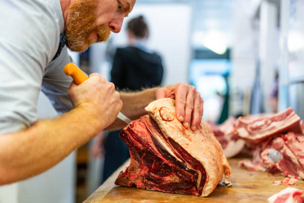 Food preparation in traditional UK Butchers shop. stock photo