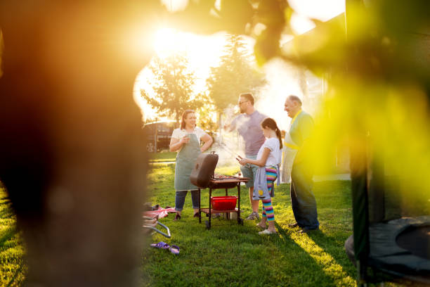 istock Meat on grill is almost ready while family stands around it waiting to be ready. 996319474
