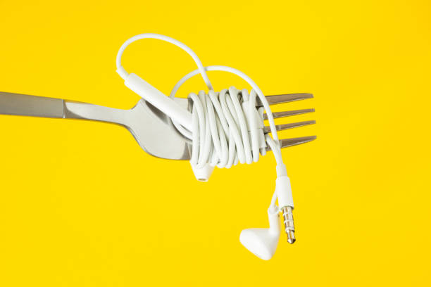 istock White headphones and fork on a yellow background 996320520
