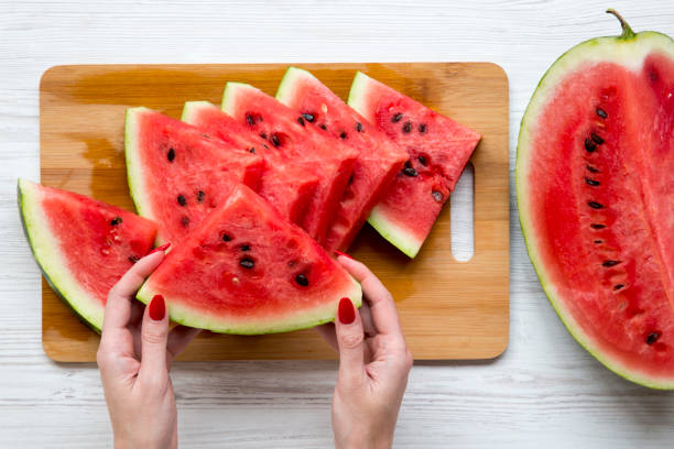 istock Women's hands hold a piece of watermelon, view from above. 996325360