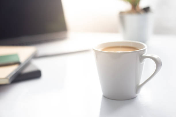 coffee cup on notebook with laptop on white table in the morning sun light ,working space - isolated on white breakfast cafe office imagens e fotografias de stock