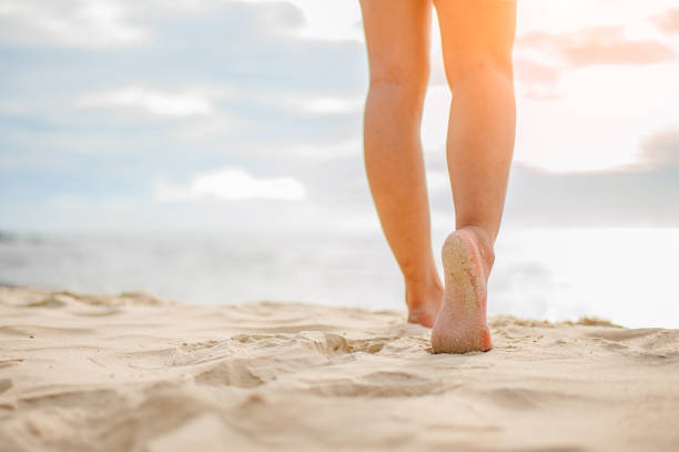 istock Woman walking on the beach at sunset. 996344740