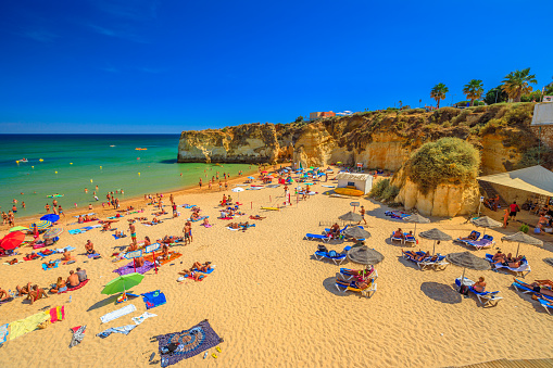 Lagos, Portugal - August 21, 2017: aerial view of Praia Dona Ana in Lagos. People sunbathing on popular Dona Ana Beach. Summer holidays in Algarve Coast, Portugal. Pillars and sandstone on background.