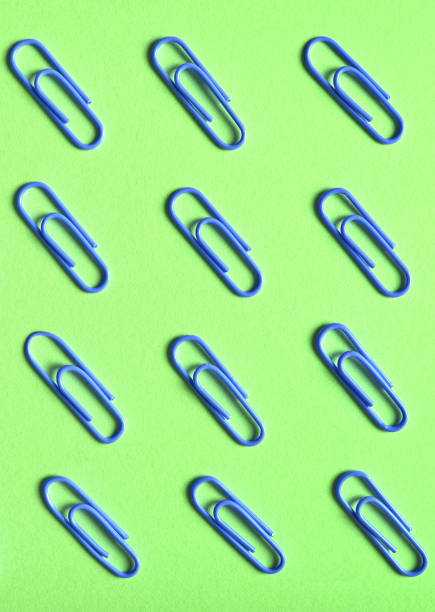 istock Violet paper clips isolated on green background, close up, copy space. Top view, flat lay. Back to school, college, education concept 996380106