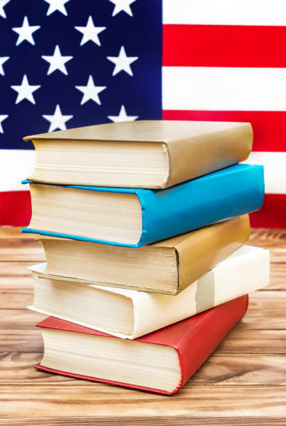 istock Stack of books on the table against american flag. American education. 996380466