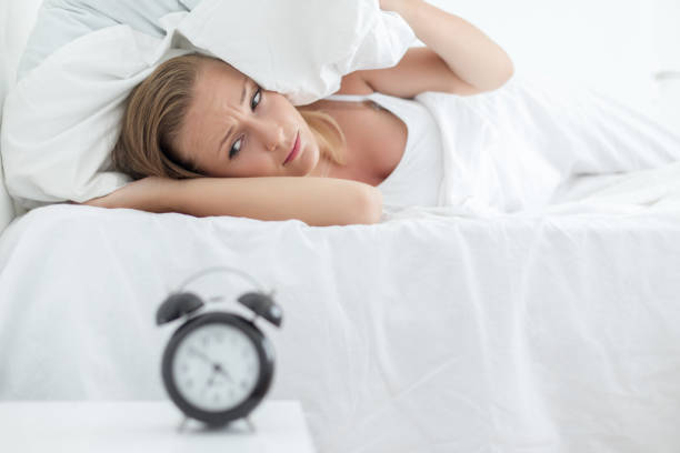 istock Sleepy girl looking at alarm clock 996401424