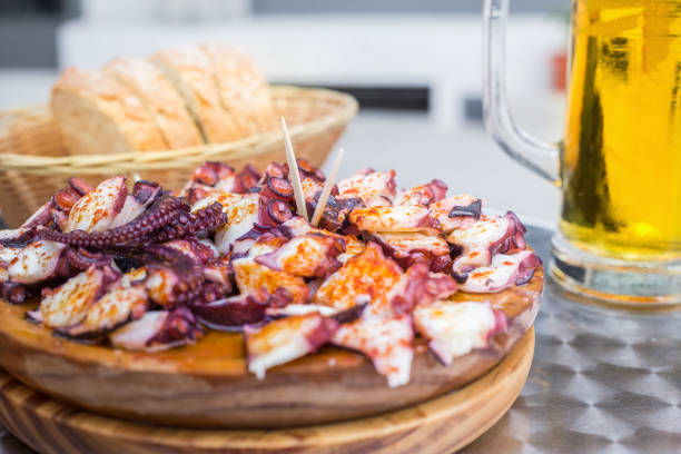 Tasty Wooden plate of galician style cooked octopus with paprika and olive oil. Pulpo a la gallega. Tasty Wooden plate of galician style cooked octopus with paprika and olive oil. Pulpo a la gallega. galicia stock pictures, royalty-free photos & images