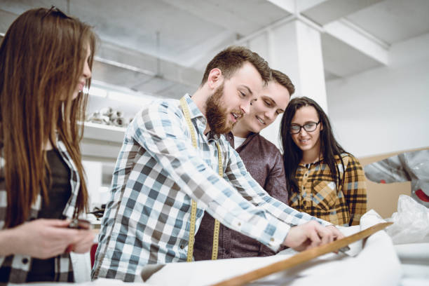 istock Chief Designer Showing Apprentices How To Cut And Sew Textile Materials 996413358