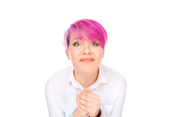 Expressive woman with pink short hair holding hands together and begging with pity looking at camera isolated on white background