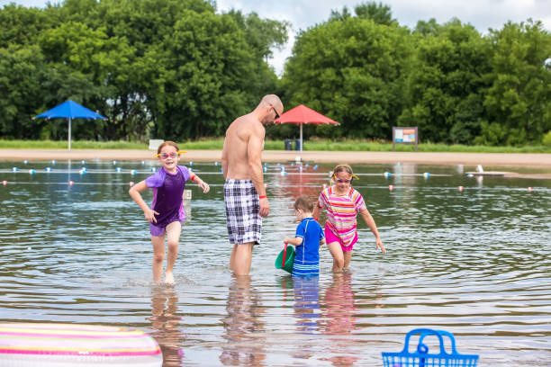 istock Father & Three Young Children Playing in Water at Beach 996416272