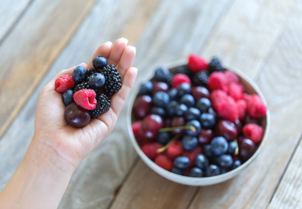 istock Flat lay fresh berries in tiny woman hand and bowl filled with berries. 996422230
