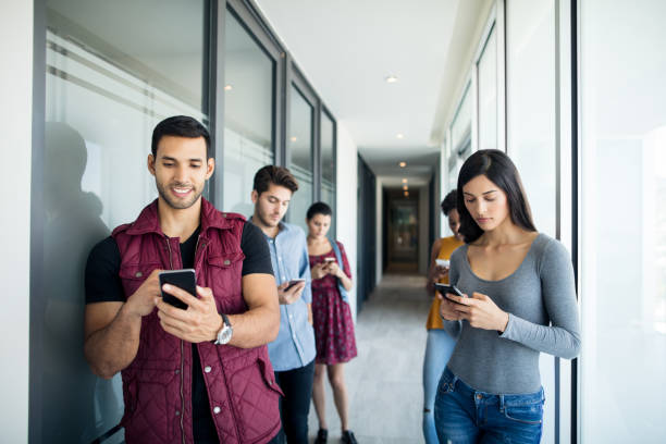 istock Young people standing on corridor and using mobile phones 996426618