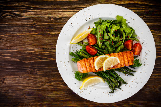 salmone alla griglia con asparagi e rucola su tavolo di legno - salmon dinner foto e immagini stock