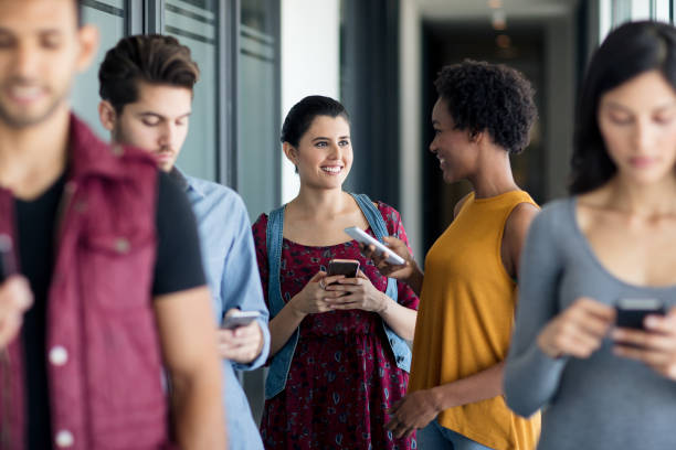 istock Young people standing on hall talking and using mobile phones 996437498