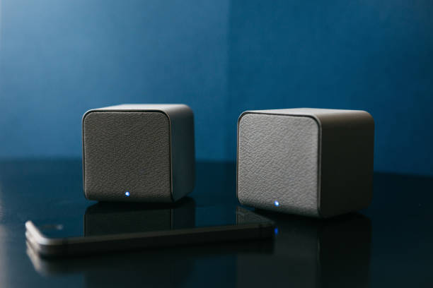 istock Wireless speakers and a cell phone next to them on a dark background. Modern technology for listening to music from a mobile phone 996437552
