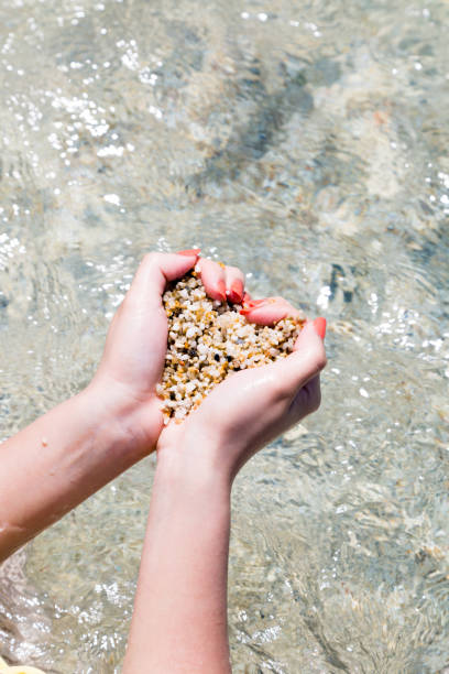 istock Beach sand in female hands by the sea, 996437558