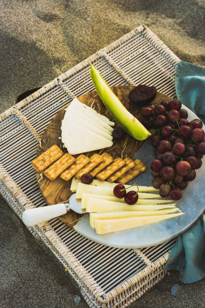 istock Seaside beach picnic on sand concept, bamboo table with cheese platter, 996437916